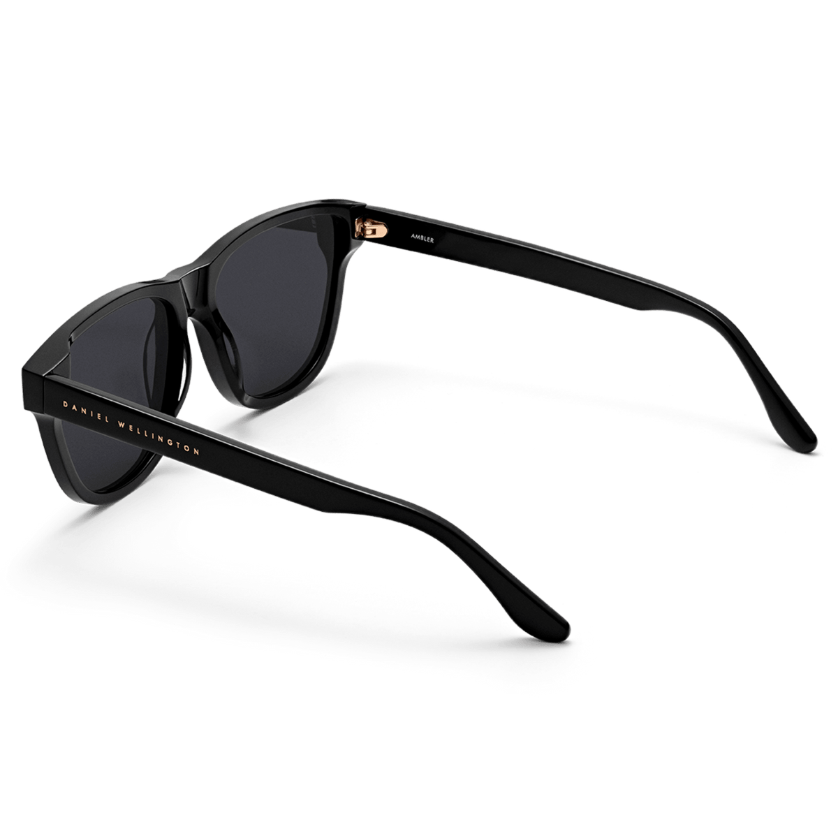 Ambler Bio-Acetate Black sunglasses shown from a rear angle, highlighting the deep black bio-acetate frame, dark lenses, and gold Daniel Wellington branding on the arm.