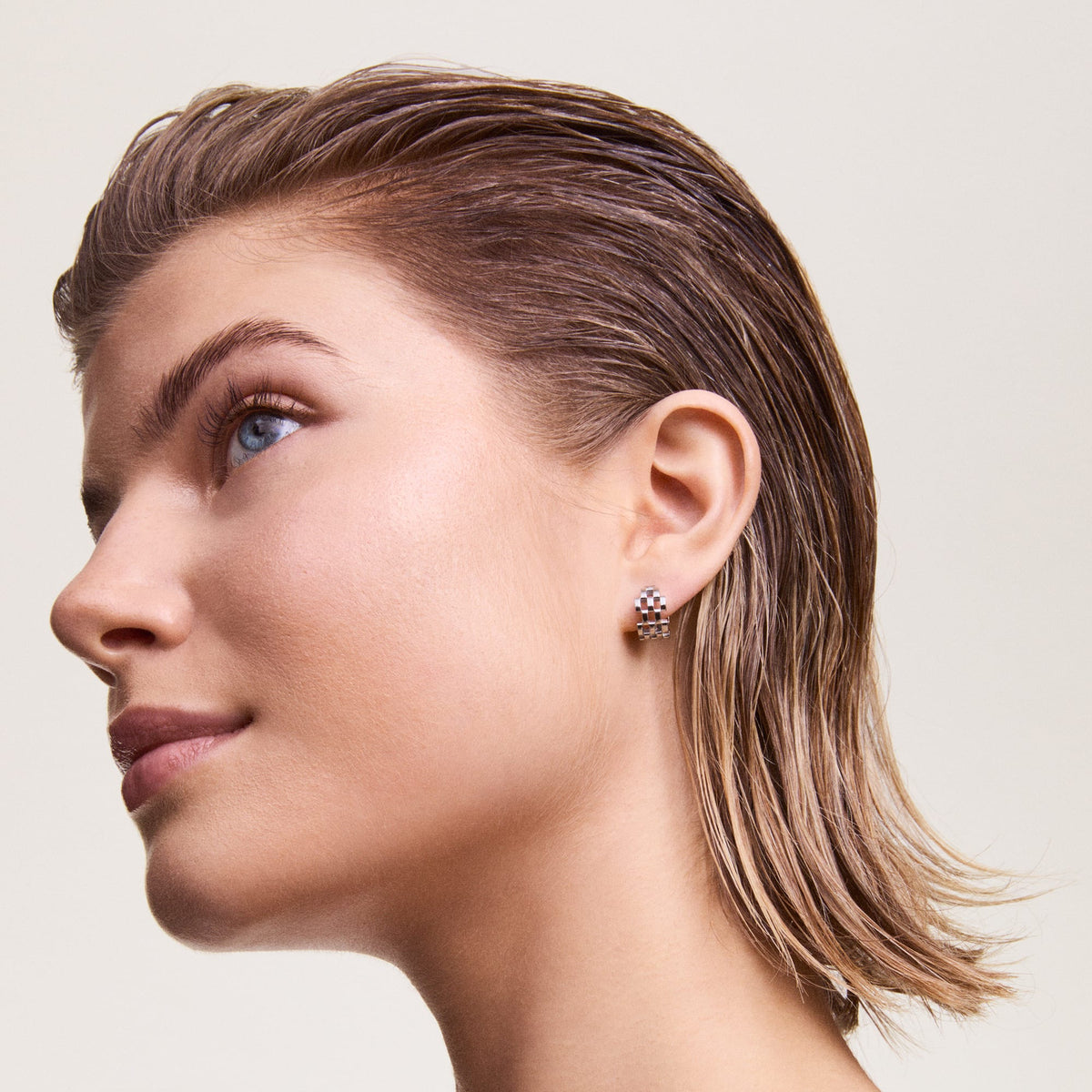 A person wearing a 5-link silver earring with a polished stainless steel finish and distinctive link pattern, styled for a modern, elegant look.