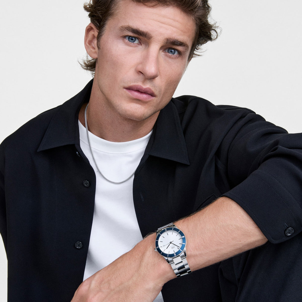 A man wears the Tide Mesh Necklace Silver 2.8, a fine silver mesh chain crafted from 316L stainless steel, styled with a white T-shirt and black shirt for a modern, understated look.