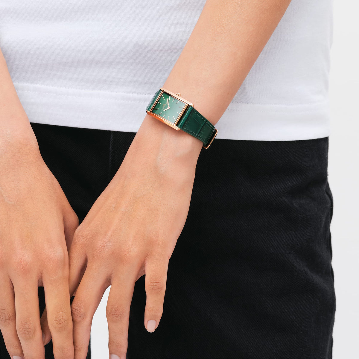 A woman wears the Bound Crocodile Emerald Sunray Rose Gold watch, featuring a rectangular rose gold case, emerald green sunray dial, and deep green crocodile pattern leather strap.