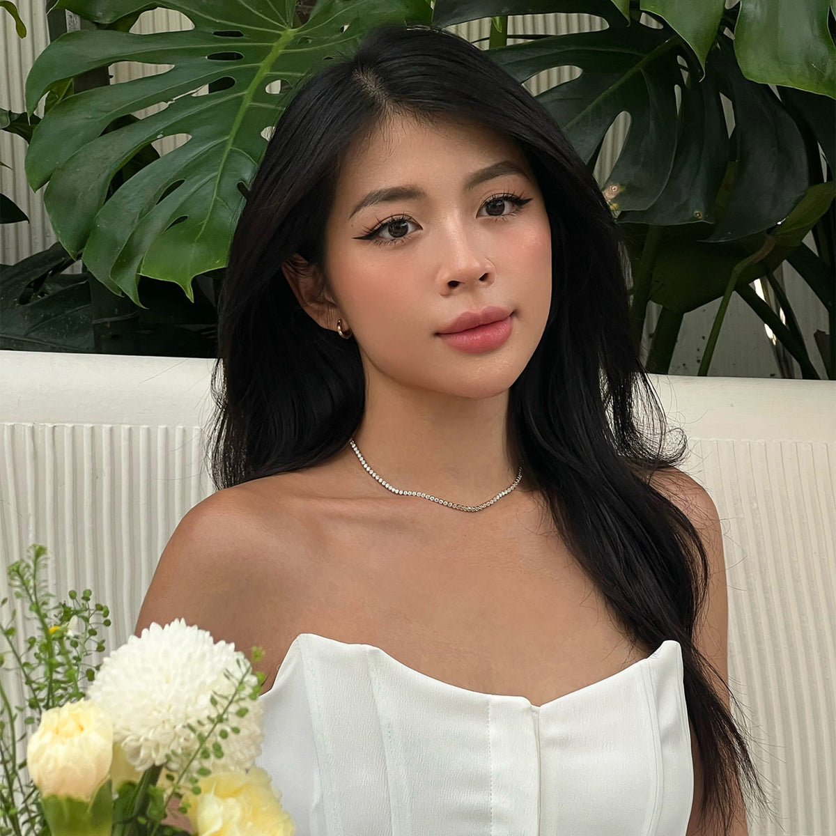 Classic Tennis Necklace Gold styled on a woman wearing a white strapless dress, highlighting the necklace’s delicate row of crystals and elegant gold finish, perfect for formal occasions or celebrations.