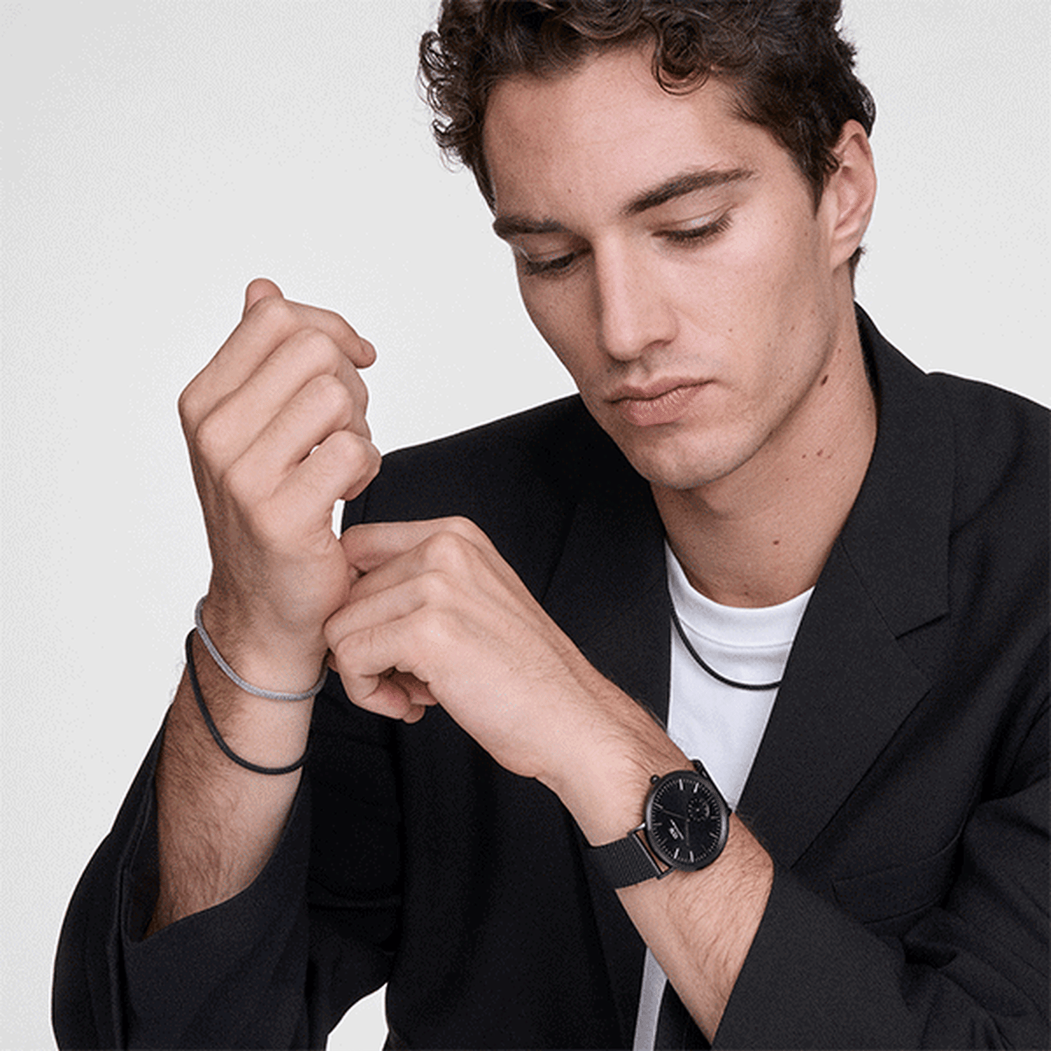 A man wearing the Tide Mesh Bracelet Sterling 2.8 on his wrist, styled with a black blazer, white shirt, and a matching watch for a refined, modern look.