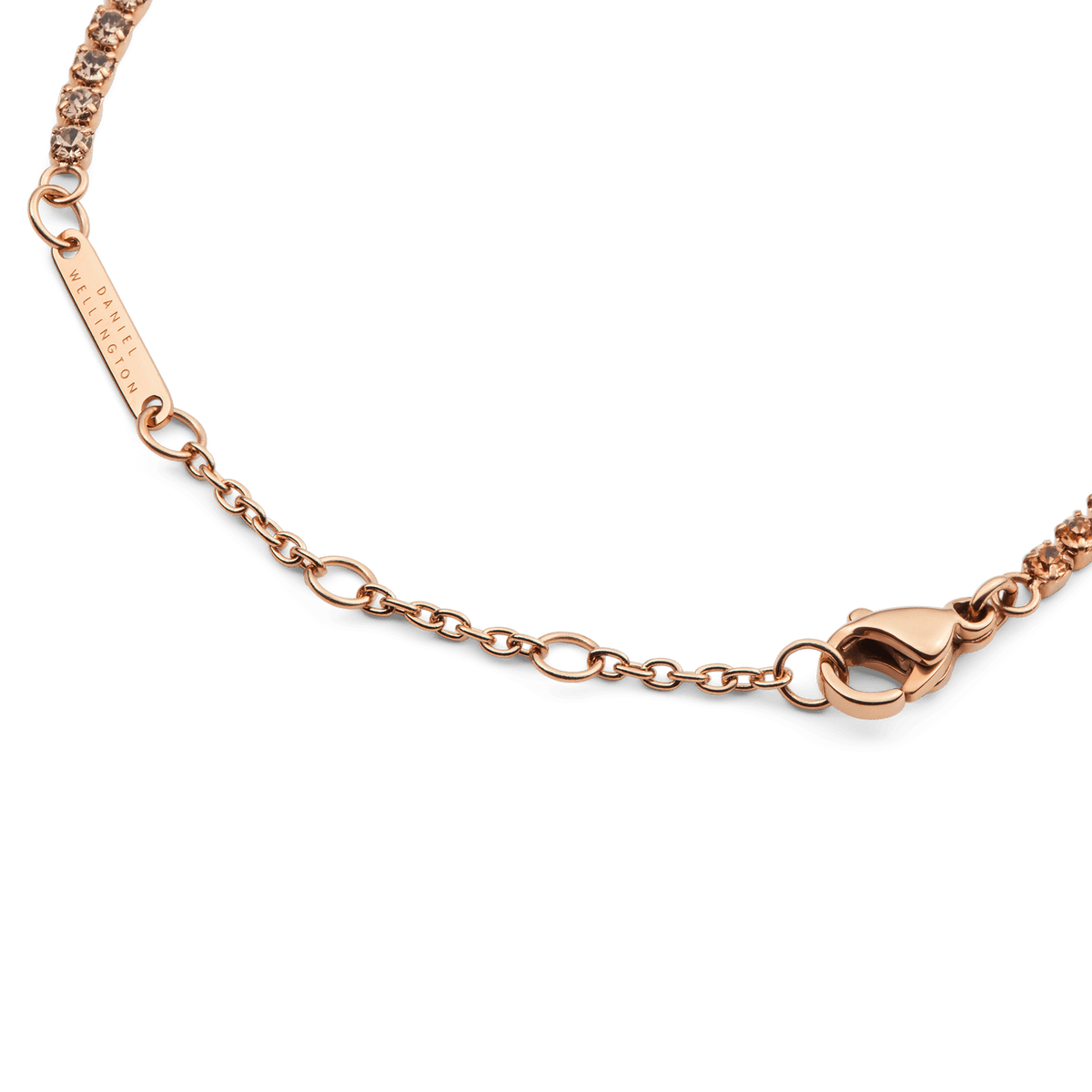 Detail of the Classic Tennis Bracelet Apricot Rose Gold, showing the adjustable rose gold chain, secure lobster clasp, and Daniel Wellington branded tag.