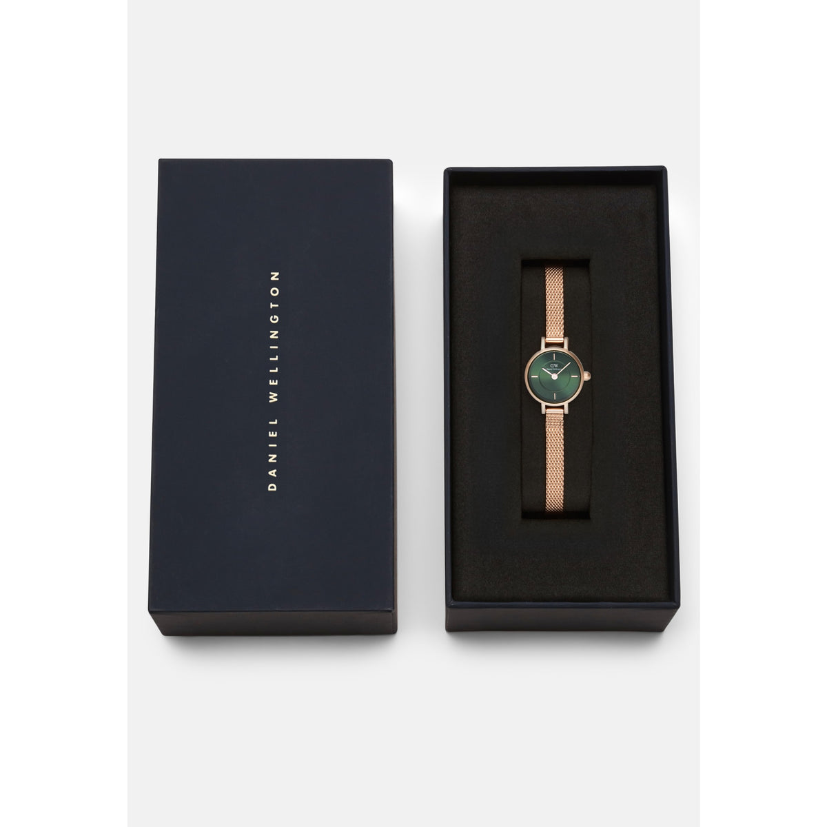 Petite Mini Emerald Melrose watch with an emerald green dial and rose gold mesh strap, elegantly presented in a black Daniel Wellington gift box.