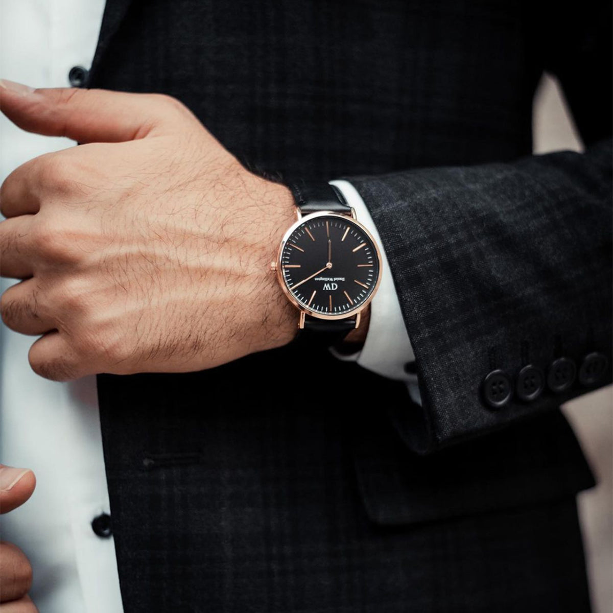 A man wearing the Classic Sheffield Black Rose Gold watch with a black leather strap and minimalist black dial, styled with a dark suit for a sophisticated look.