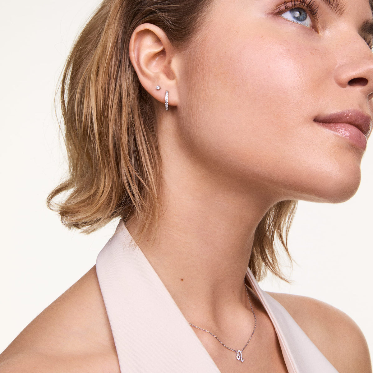 A woman wears the Crystal Hoop Earring Silver, a petite polished silver hoop set with sparkling cubic zirconia crystals, styled for an elegant everyday look.