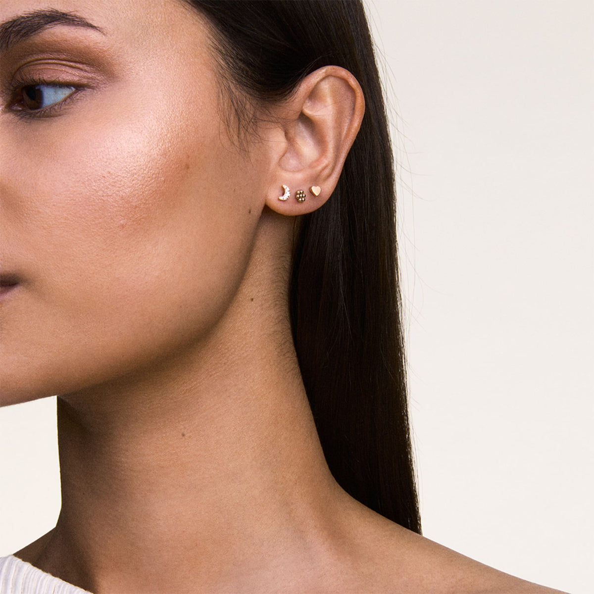 Woman wearing the Crystal Moon + Flower + Heart Rose Gold Set, featuring three dainty rose gold stud earrings in moon, flower, and heart shapes, styled together on one ear for a refined, modern look.