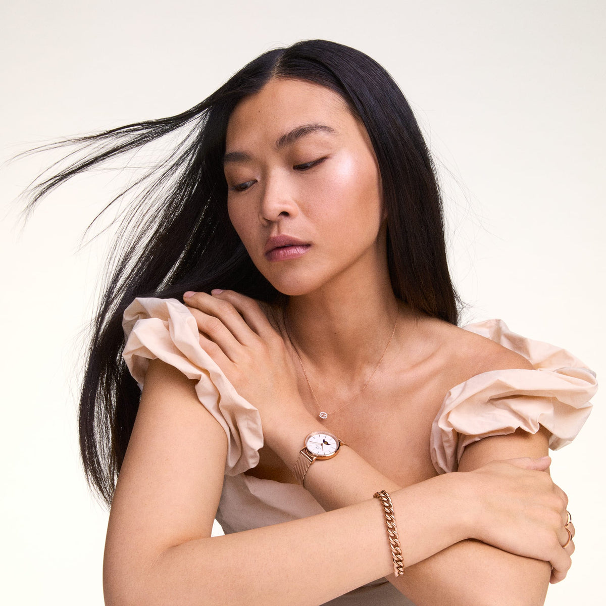 A woman wears the Crystal Zodiac Chain Necklace Silver with a sparkling Cancer zodiac pendant, styled alongside a rose gold watch and bracelet for an elegant look.