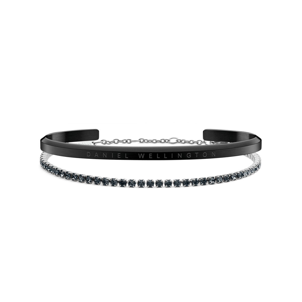 A sleek black Daniel Wellington cuff engraved with the brand name is paired with a silver tennis bracelet featuring a row of sparkling stones, displayed together to showcase their modern, elegant contrast.