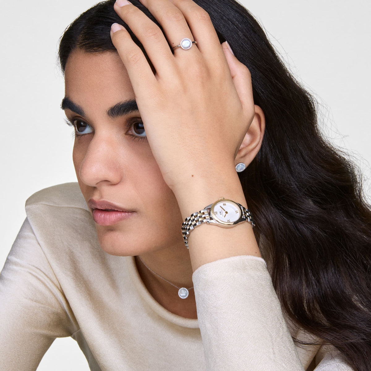 Woman wearing Daniel Wellington Ophelia Mini Two Tone Gold watch with gold-silver bracelet and sunray white dial.