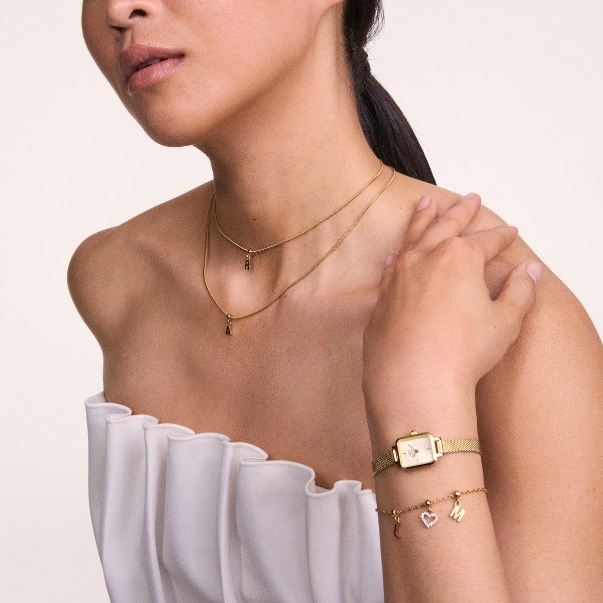 Woman wearing Quadro Mini Evergold Champagne gold mesh strap watch with champagne dial, styled with gold jewellery.