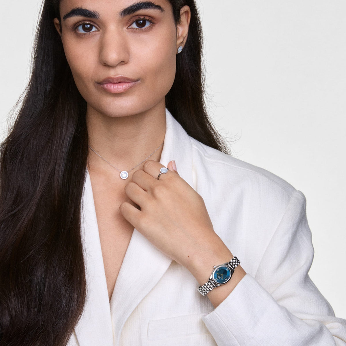 Woman wearing Ophelia Mini Arctic Silver watch with blue oval dial and silver bracelet, styled with matching jewellery.