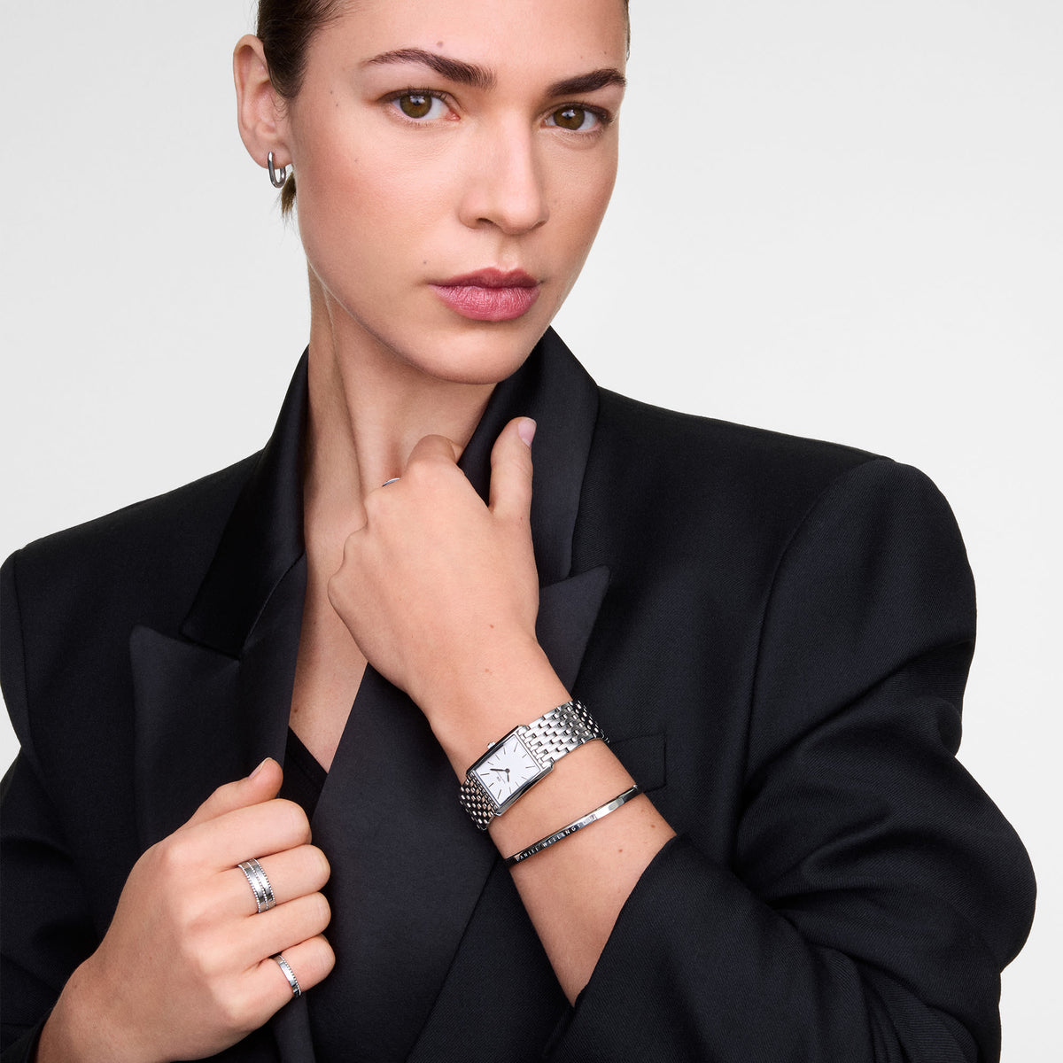 Woman wearing a black blazer styled with the Classic Aura Duo Ring Silver on her finger, showcasing its dual rows of sparkling cubic zirconia crystals and polished silver finish, paired with a silver watch and matching jewellery for an elegant, modern look.