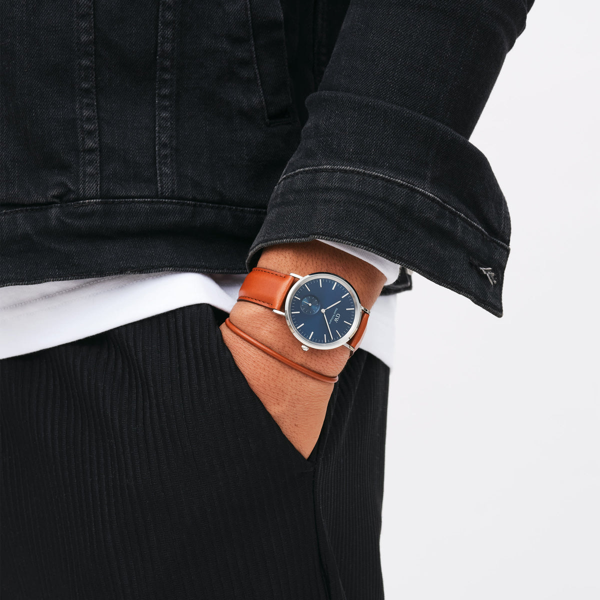A person wearing the Classic Multi-Eye St Mawes Arctic Silver watch with a blue dial and brown leather strap, styled casually with a black jacket and hand in pocket.