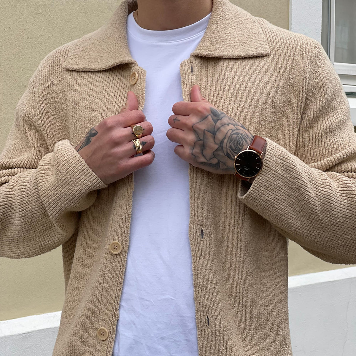 Man wearing the Classic St Mawes Amber Rose Gold watch with a brown leather strap and sunray dial, styled with a beige cardigan and white T-shirt.