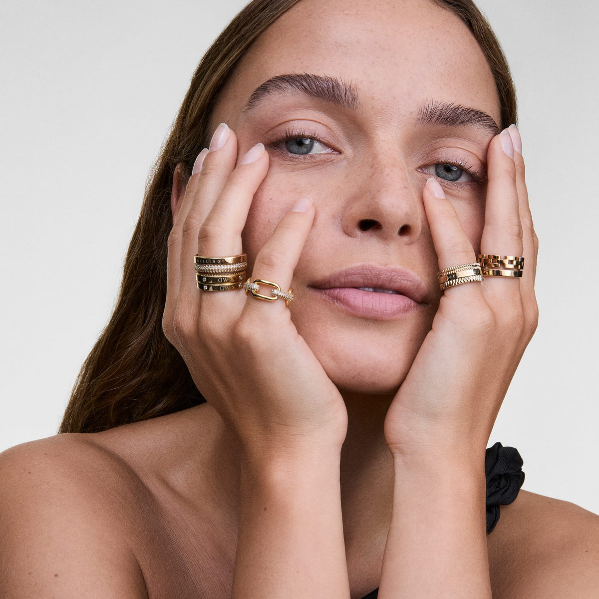 A woman wears the Crystal Link Ring Gold on her right hand, showcasing its chunky gold-plated chain links and sparkling cubic zirconia crystals, styled alongside other gold rings for a modern, layered look.
