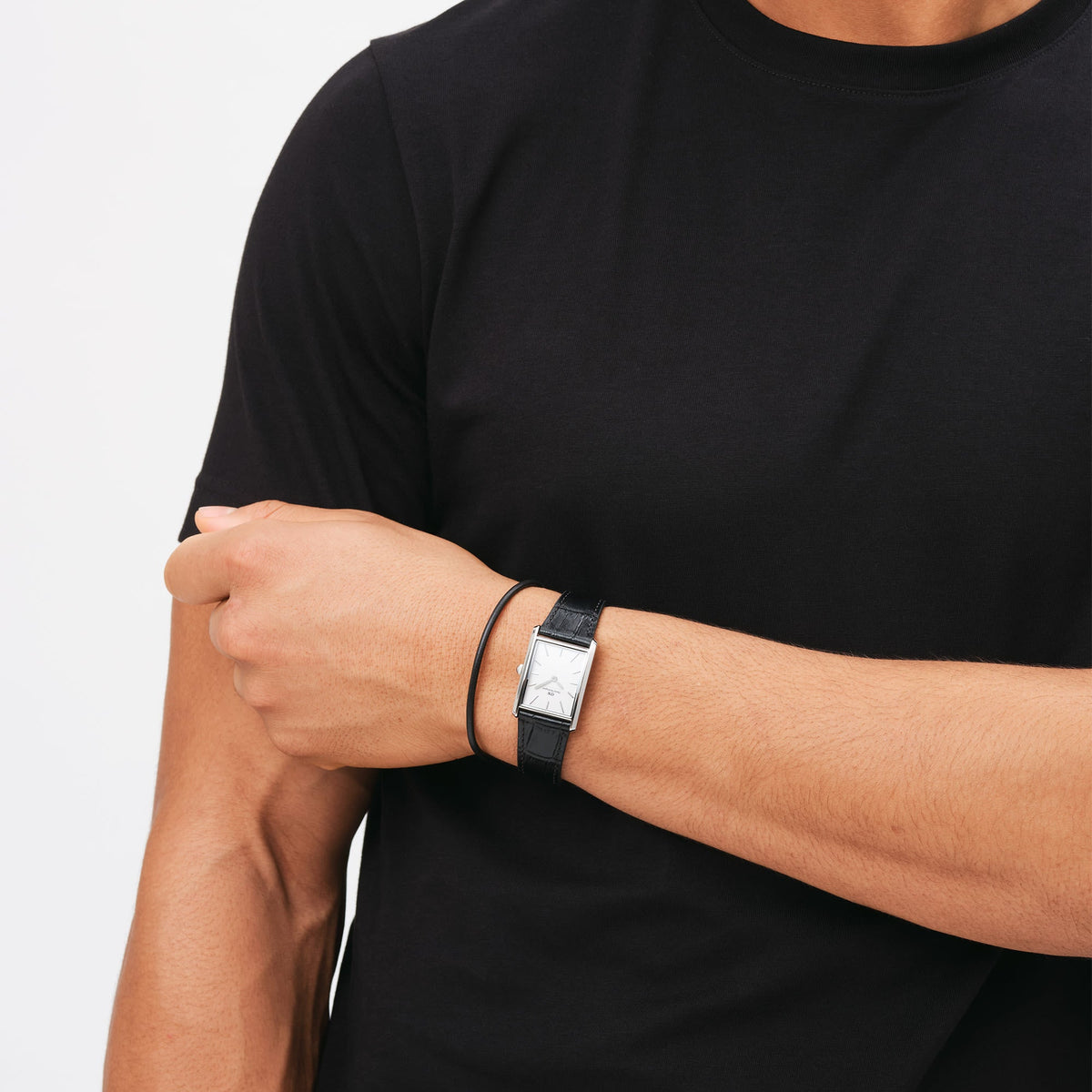 A person wearing the Sheffield Bracelet Silver, a slim black leather bracelet with a polished silver clasp, styled alongside a classic rectangular watch on the wrist.