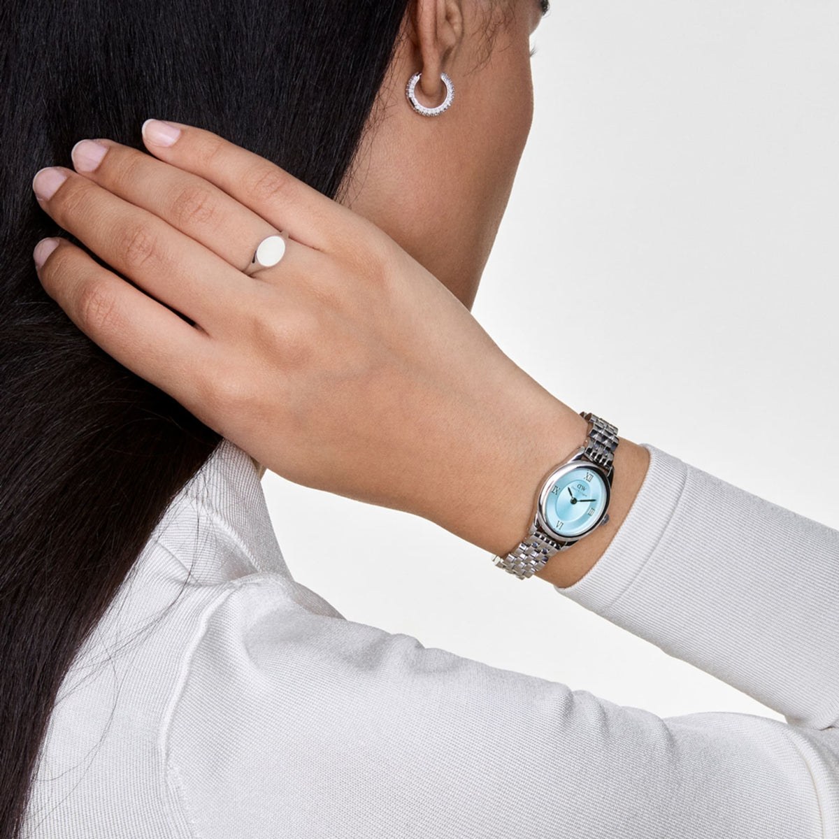 Woman wearing Ophelia Mini Ice Blue Silver watch with oval case, sunray blue dial, and polished silver strap on wrist.