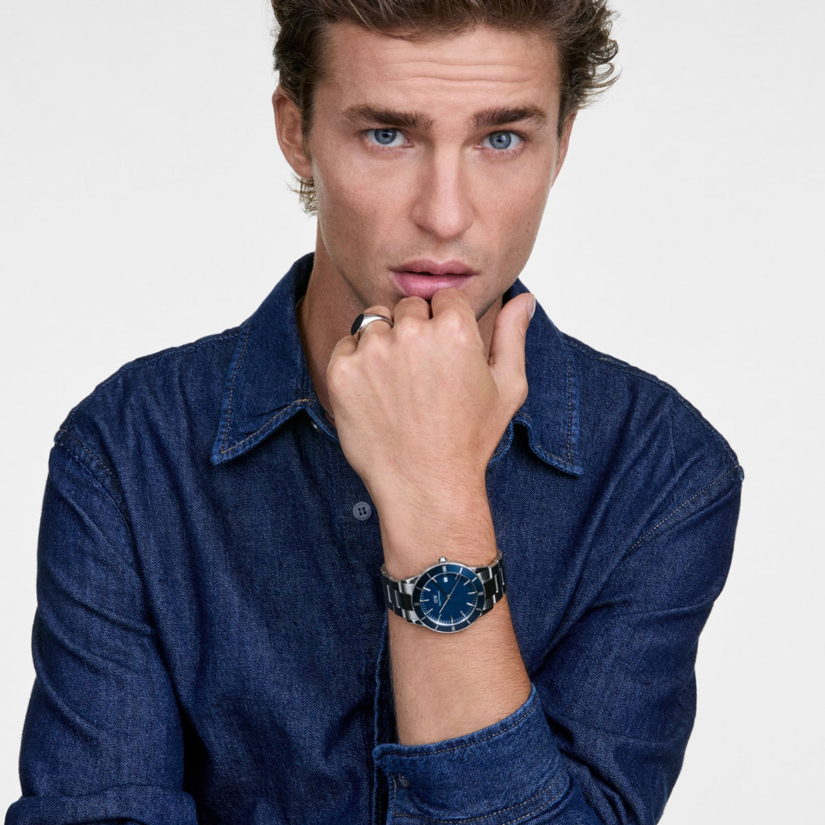 A man wearing the Iconic Paradigma Link Blue Enamel watch, featuring a deep blue dial and silver stainless steel bracelet, styled with a casual denim shirt for a modern, versatile look.