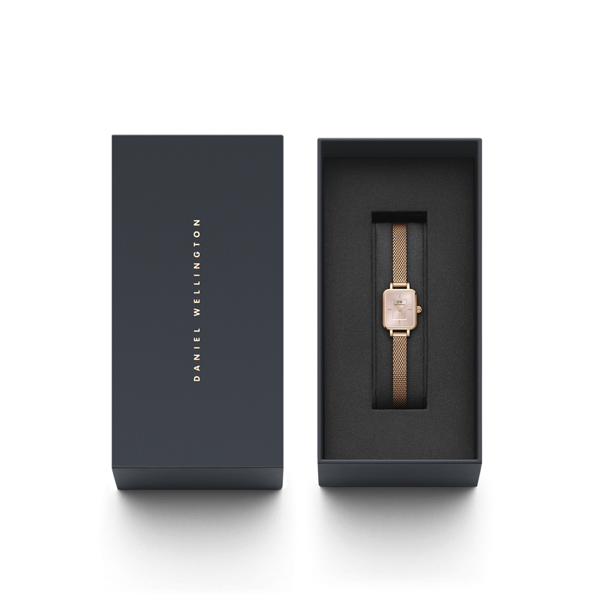 Quadro Mini Melrose Blush women’s watch with a blush pink rectangular dial and rose gold mesh strap, elegantly presented in a dark Daniel Wellington gift box.
