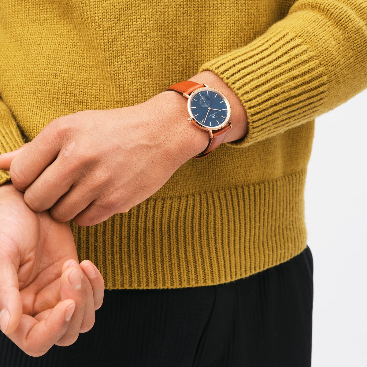 A man wearing the Classic Multi-Eye St Mawes Arctic Rose Gold watch with a deep blue dial, rose gold case, and brown leather strap, styled with a mustard jumper.