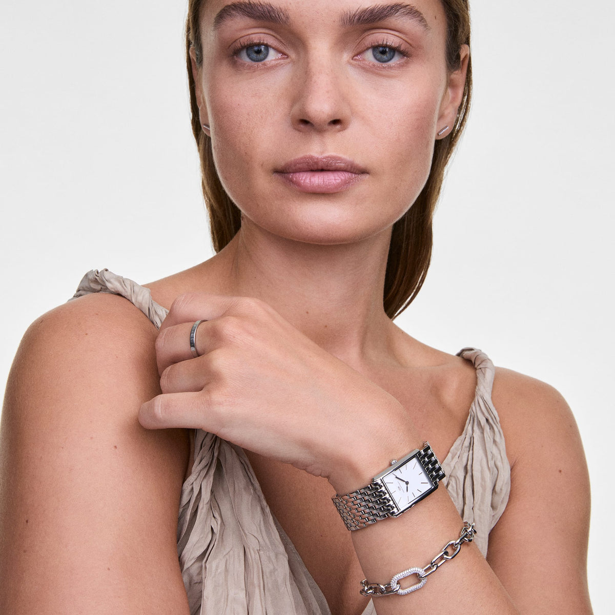 Woman wearing the Crystal Link Bracelet Silver on her wrist, showcasing its chunky silver chain and crystal-embellished link, styled with a silver watch and a neutral sleeveless top.