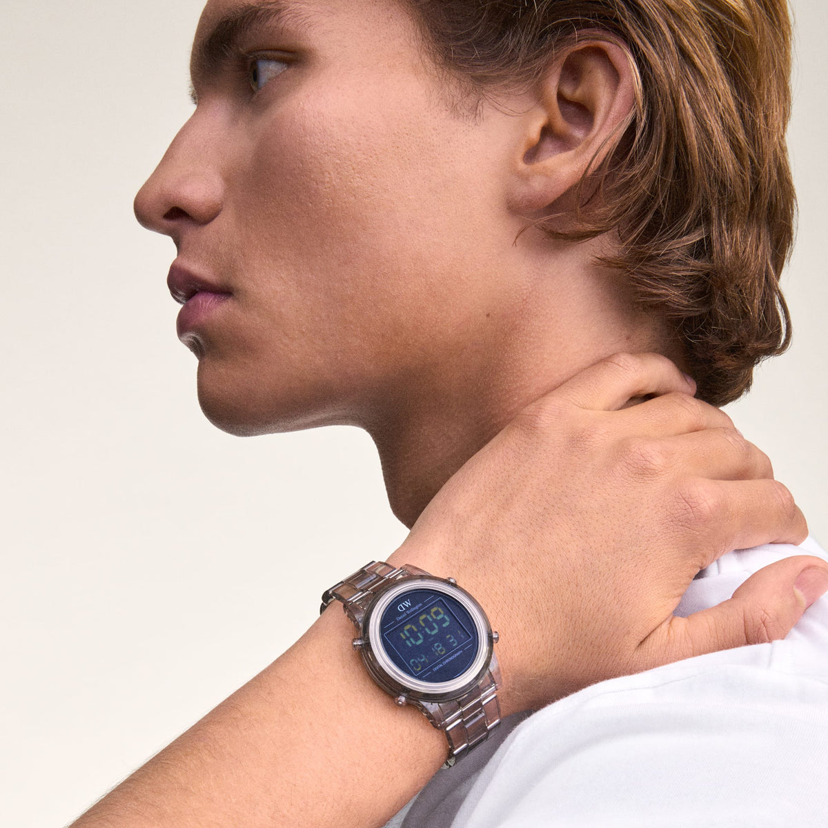 A man wearing the Daniel Wellington Retro Digital Light Grey watch with a transparent bio-based plastic strap and bold digital display, styled with a white shirt.