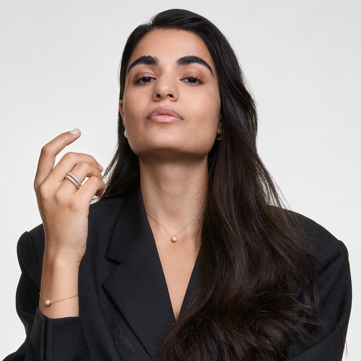 Woman wearing the Pavé Crystal Pendant Bracelet Gold on her wrist, styled with a matching pavé crystal necklace and rings, paired with a black blazer for an elegant, modern look.