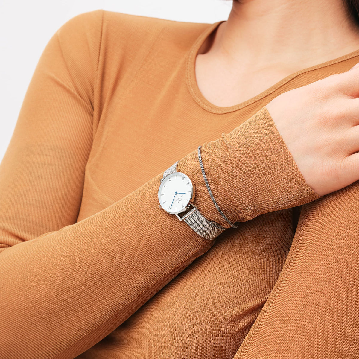 A slim silver mesh bracelet is styled on the wrist alongside a matching watch, highlighting its delicate design and minimalist elegance.