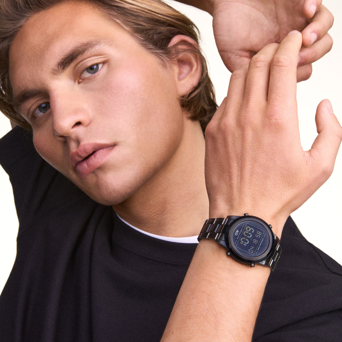 The Retro Digital Dark Grey watch by Daniel Wellington is worn on the wrist, highlighting its dark grey stainless steel link strap and clear black digital display.