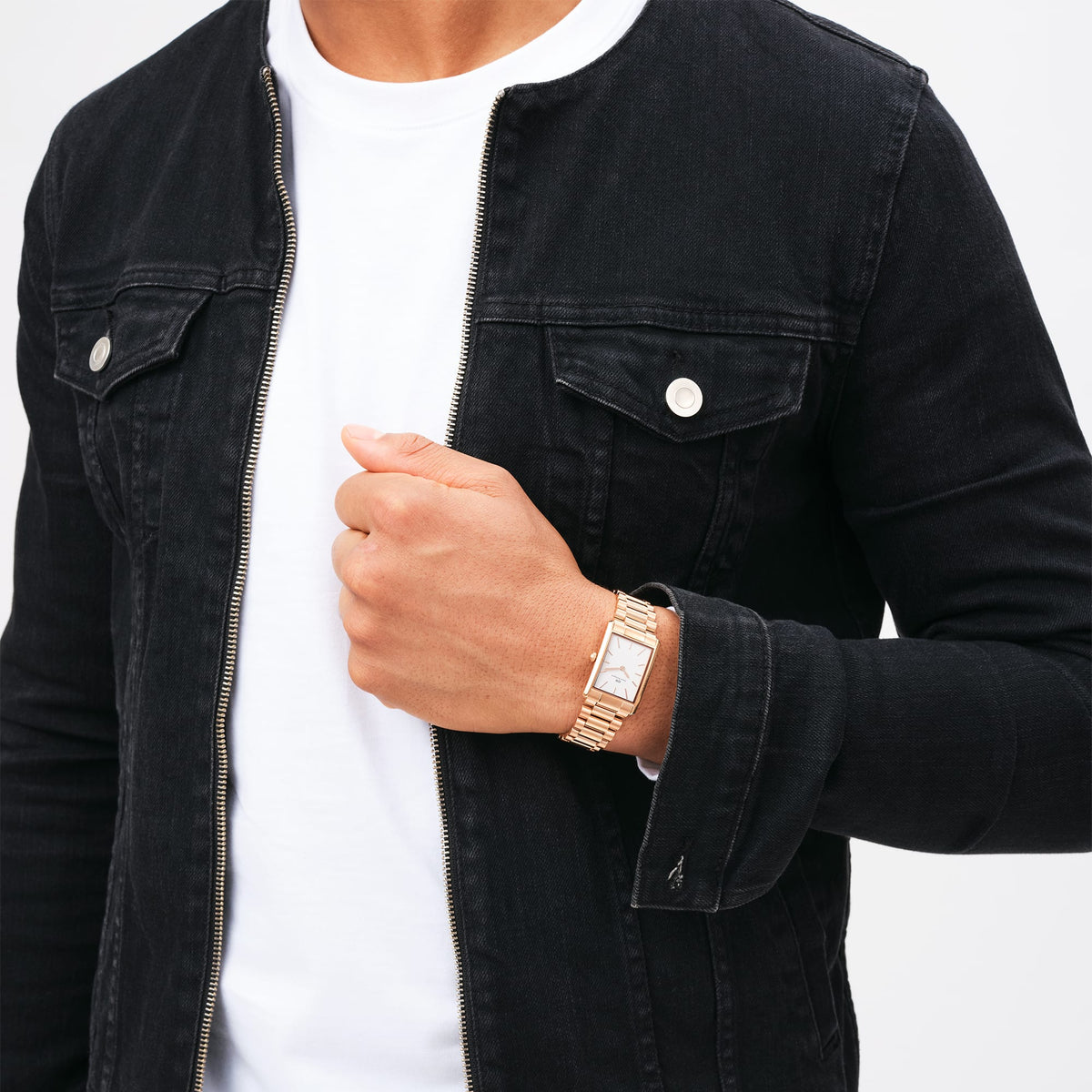 Man wearing the Bound 3-Link Rose Gold rectangular watch with a three-link rose gold bracelet, styled with a white T-shirt and black denim jacket.