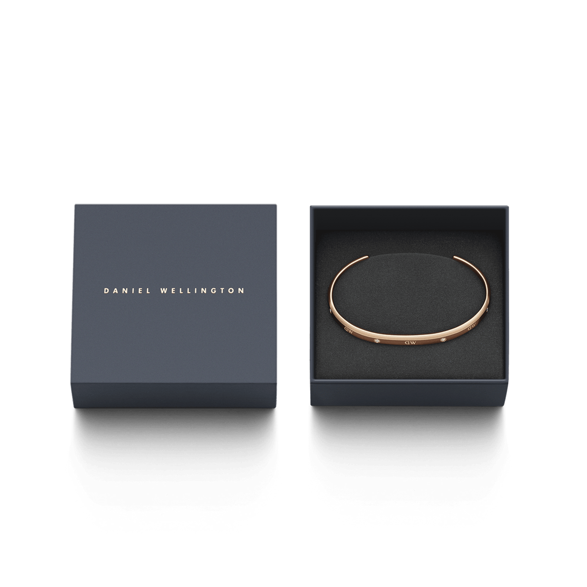 Classic Lumine Bracelet RG in rose gold, featuring a slim open cuff with sparkling crystals, elegantly presented in a navy Daniel Wellington gift box.