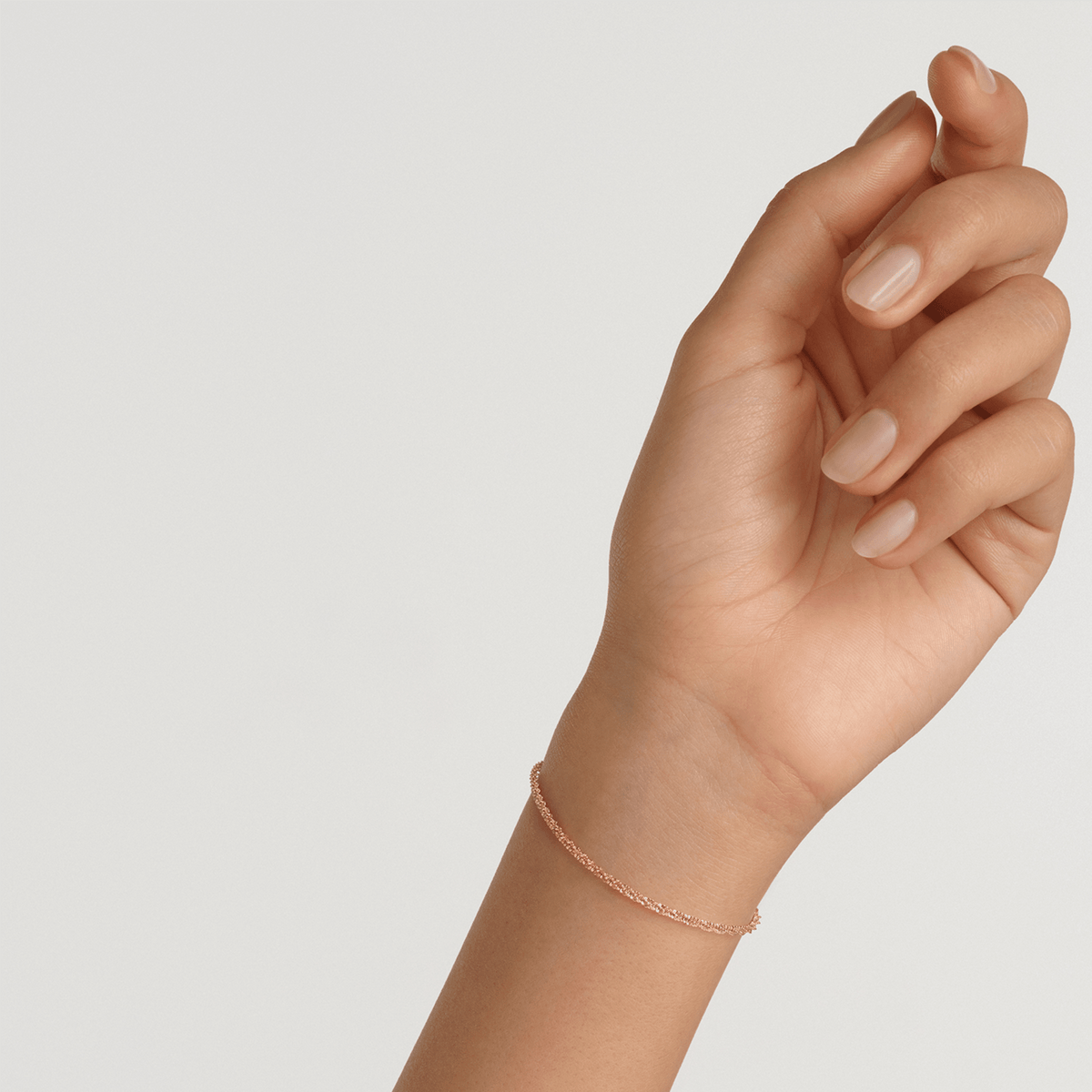 A slim rose gold twisted chain bracelet with a delicate rope design, shown worn on a wrist for a minimalist and elegant look.