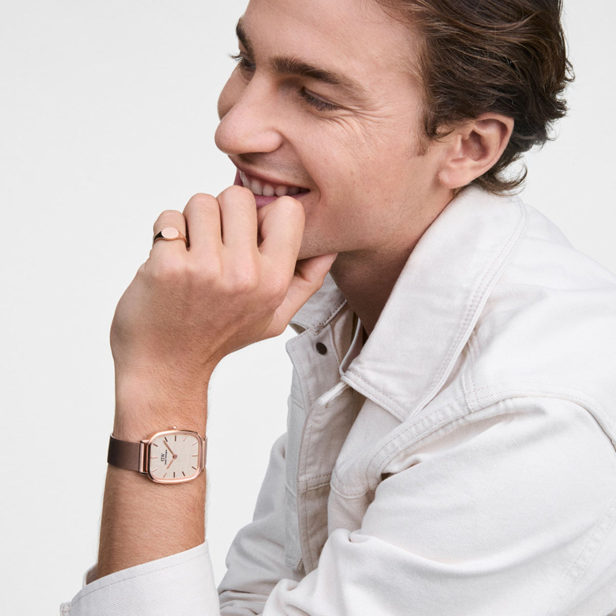 Man wearing a classic rose gold signet ring and matching watch, styled with a light denim jacket for a modern look.