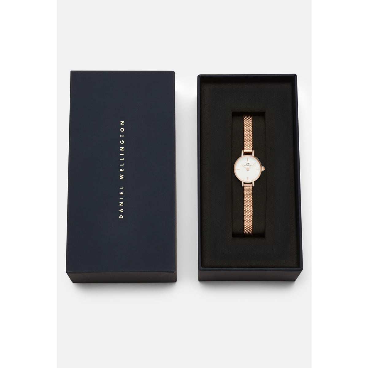 Petite Mini Melrose women’s watch with a rose gold mesh strap and white dial, elegantly presented in a black Daniel Wellington gift box.