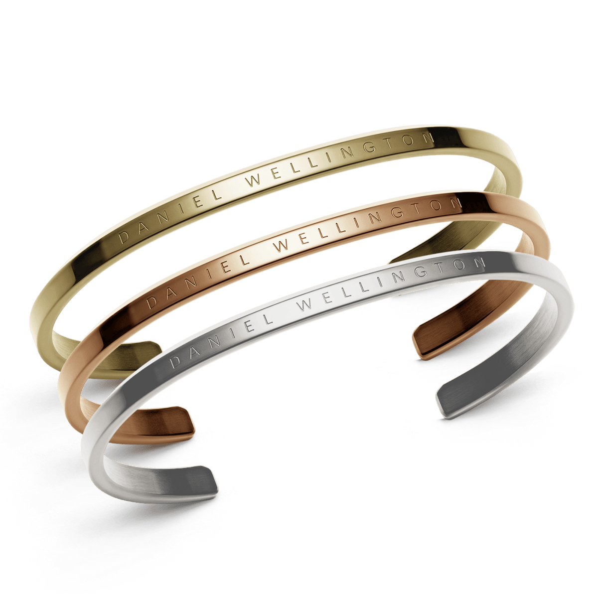 Set of three Daniel Wellington cuff bracelets in polished gold, rose gold, and silver finishes, each featuring a minimalist design with engraved branding. The trio is elegantly stacked, showcasing their refined curves and versatile metallic tones.