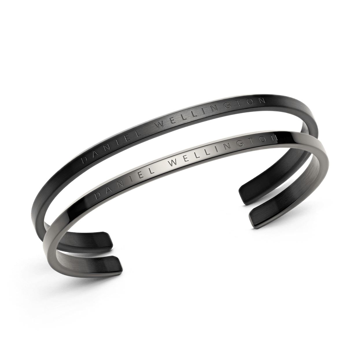 Two Daniel Wellington open cuff bracelets in black and graphite finishes, each engraved with the brand’s signature, displayed overlapping to highlight their minimalist and contemporary design.