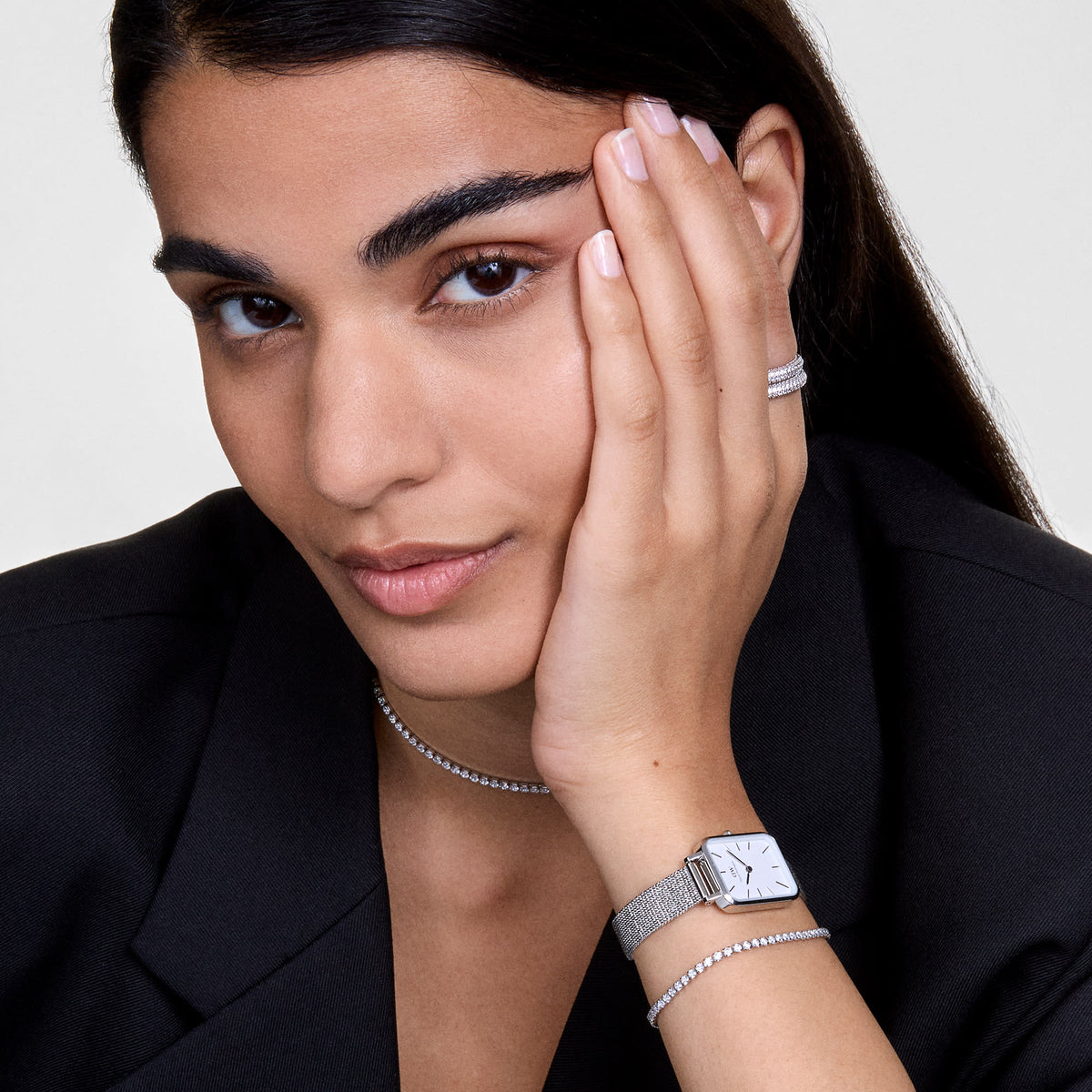 Woman wearing Quadro Pressed Sterling silver watch with rectangular dial and mesh strap, styled with elegant jewellery.