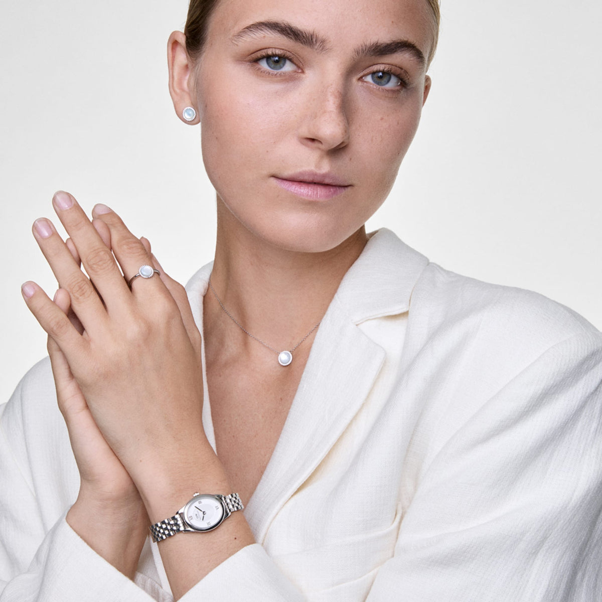 Woman wearing Ophelia Mini Silver watch with oval case and 5-link bracelet, styled with matching silver jewellery.