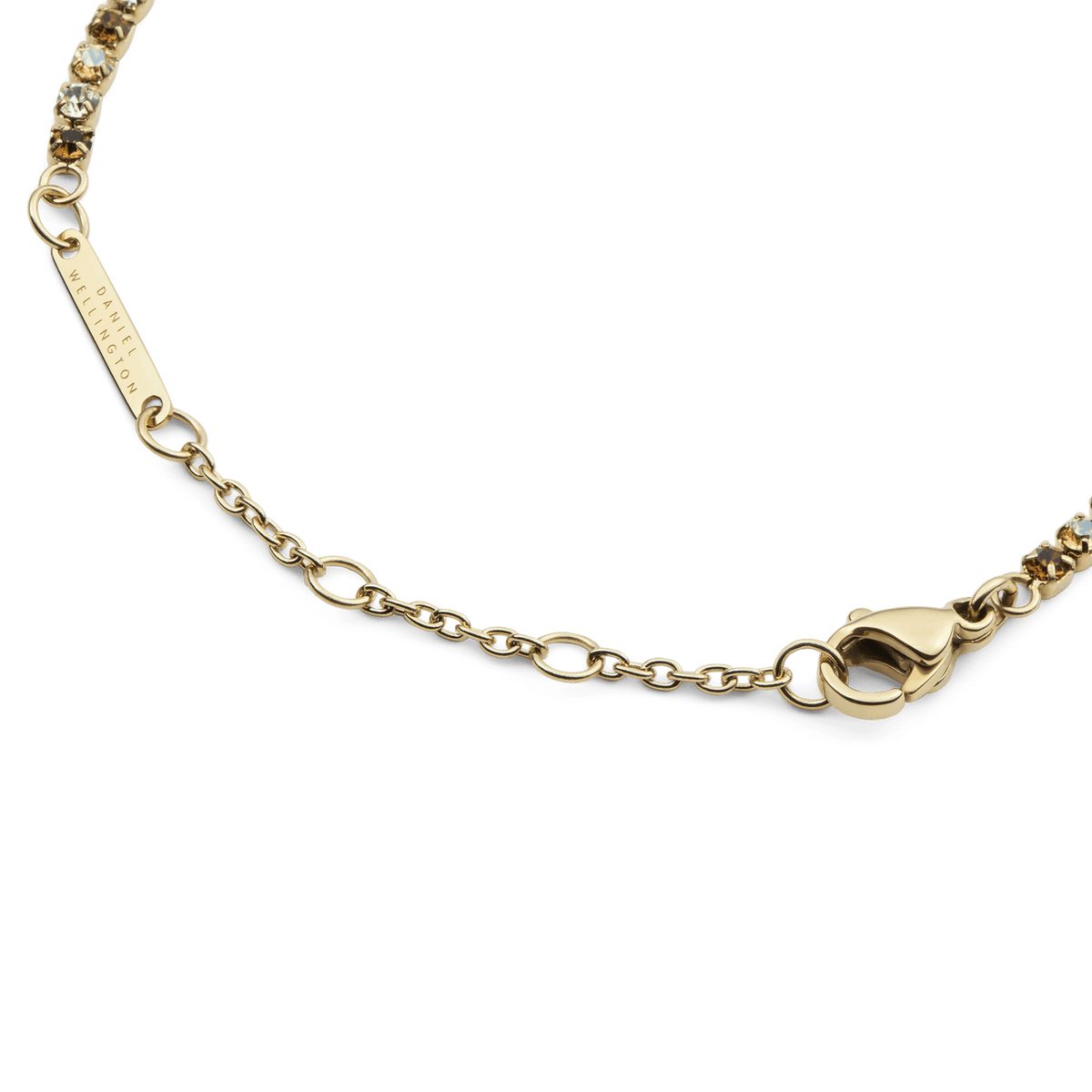 Close-up of the Classic Tennis Bracelet Honey Combo Gold, highlighting the adjustable gold chain, secure lobster clasp, and engraved Daniel Wellington tag.