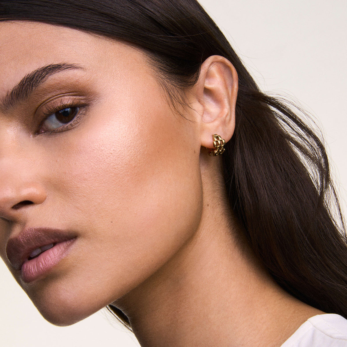 Gold 5-link earring with a geometric, interlocking design worn on the ear, showcasing its polished finish and modern style.