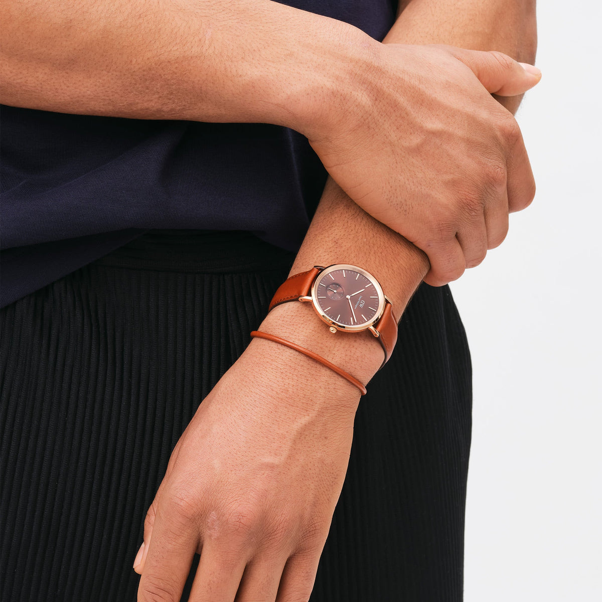 A man wearing the Classic Multi-Eye St Mawes Amber Rose Gold watch with an amber dial, rose gold case, and brown leather strap, styled with casual clothing.