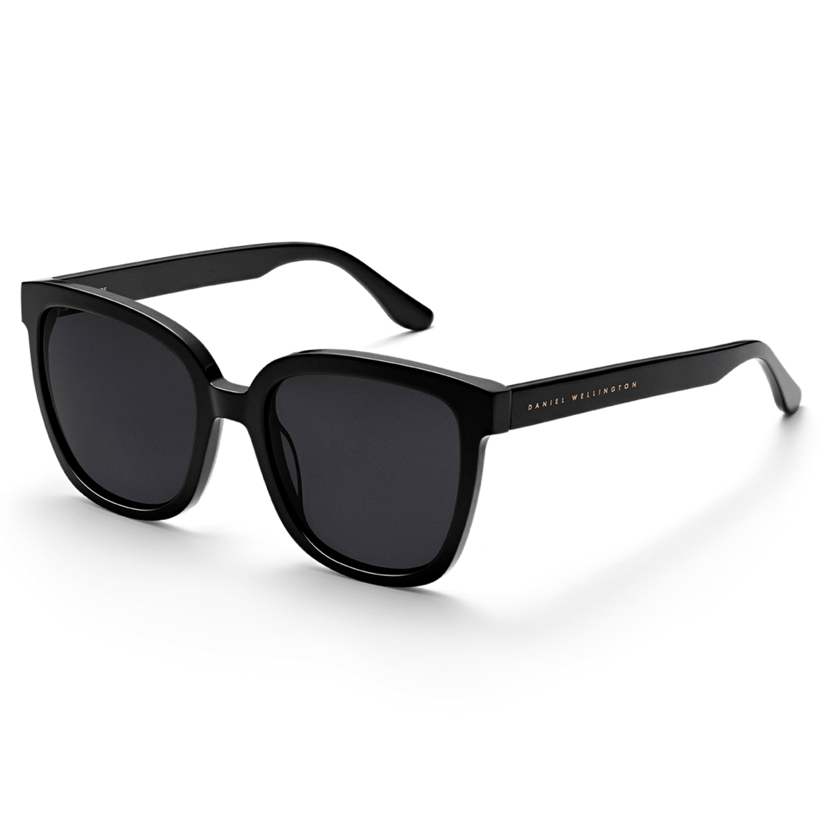 Grande Bio-Acetate Black sunglasses featuring oversized square black frames, dark nylon lenses, and subtle gold Daniel Wellington branding on the arms.