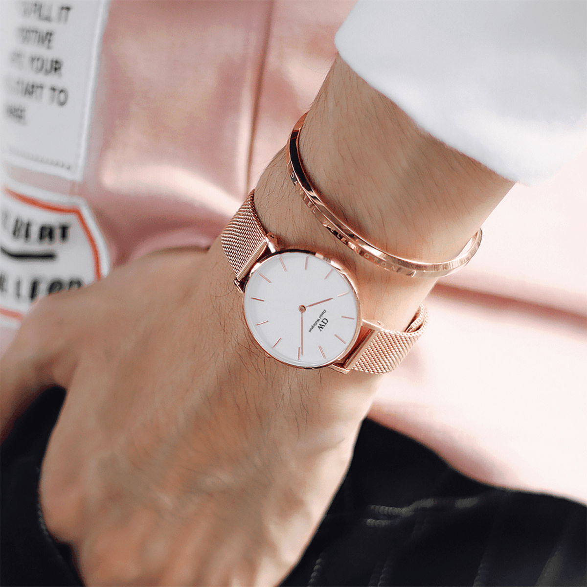 Rose gold Daniel Wellington Classic Bracelet styled with matching mesh strap watch on wrist, paired with a casual outfit.