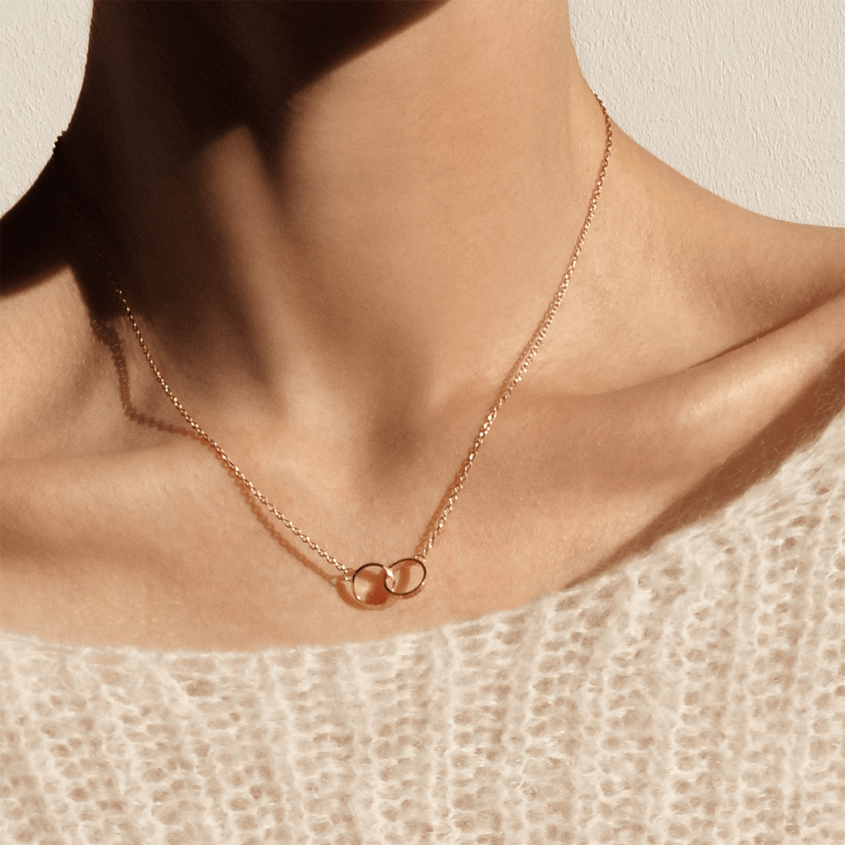 Woman wearing Elan Unity Necklace in rose gold with interlocking circles, delicate chain, minimalist jewellery styling.