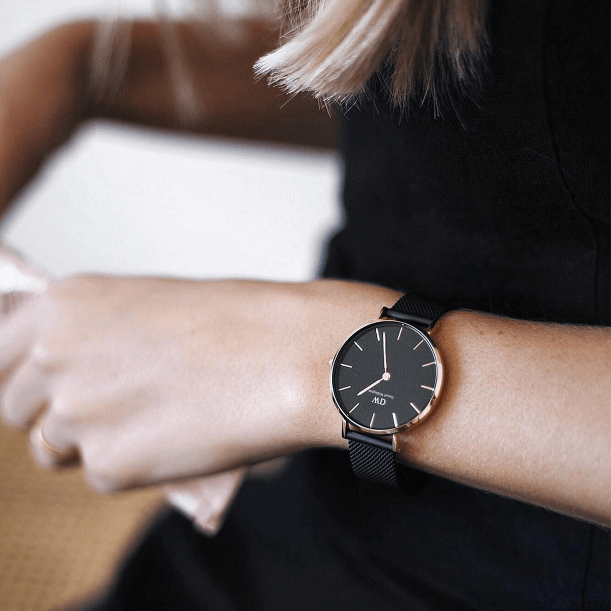 Woman wearing the Petite Ashfield watch with a matte black dial, rose gold case, and black mesh strap, styled for a modern and elegant look.