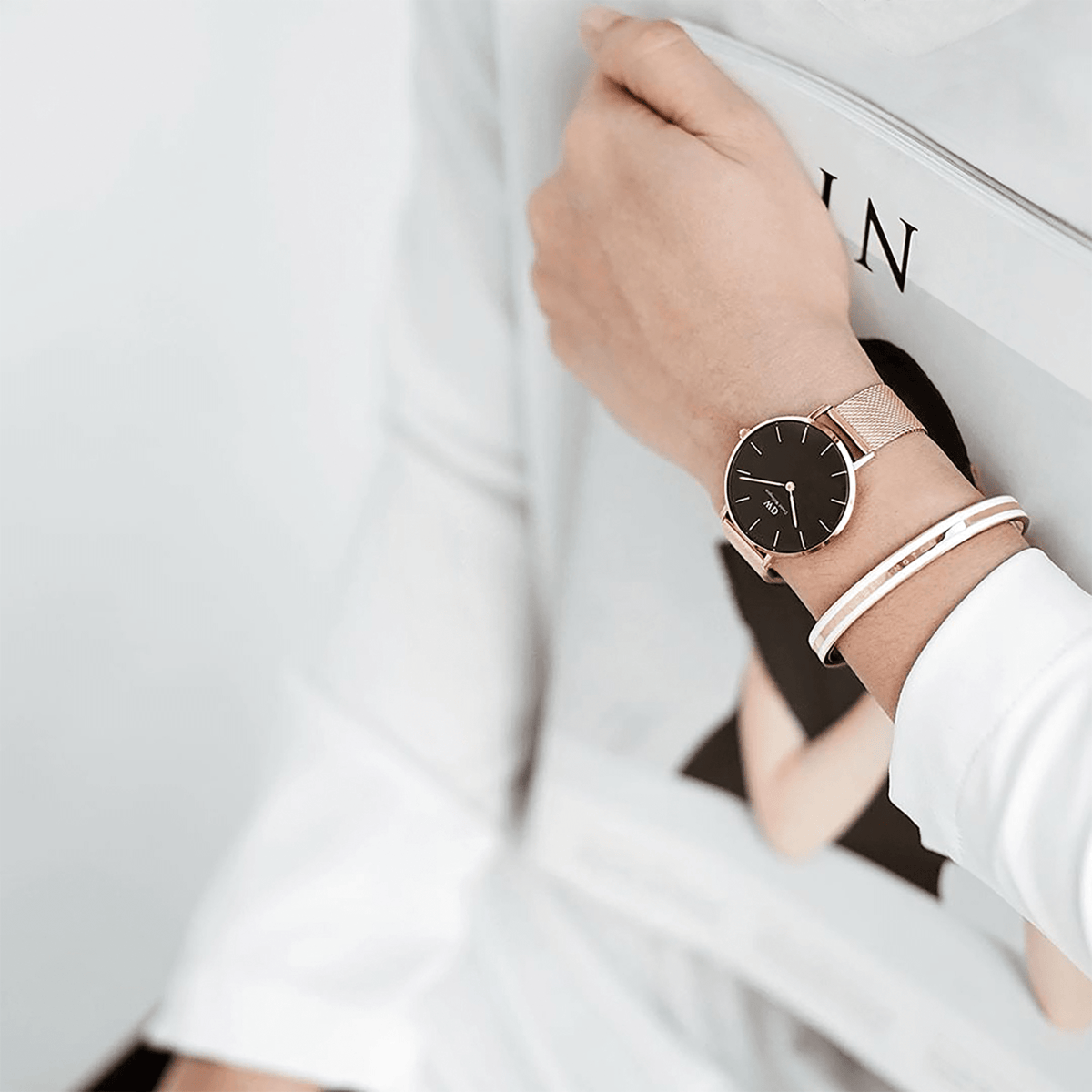 A person wearing the Emalie Slim Bracelet in rose gold with a satin white enamel inlay, styled alongside a matching rose gold mesh watch for a modern, elegant look.