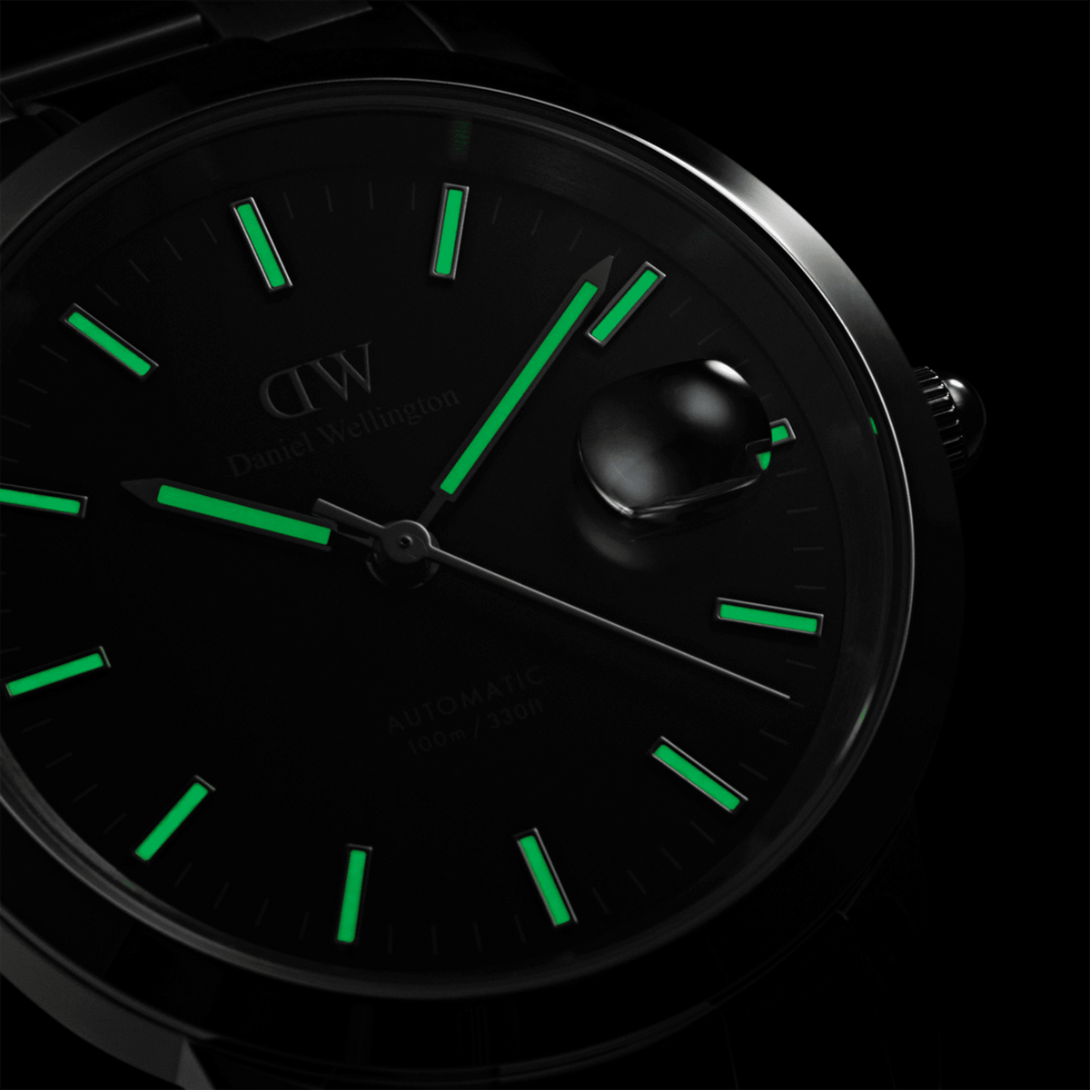 Close-up of the Iconic Link Automatic watch dial in the dark, highlighting luminous hands and hour markers with a magnified date window.