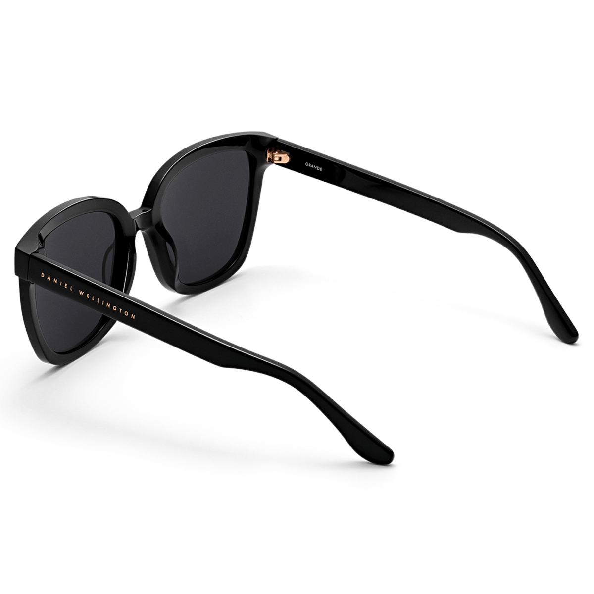 Grande Bio-Acetate Black sunglasses with glossy oversized square frames, dark lenses, and gold Daniel Wellington branding along the arm.