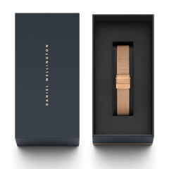 Rose gold mesh watch strap with a fold-over clasp, elegantly presented in a dark Daniel Wellington gift box.